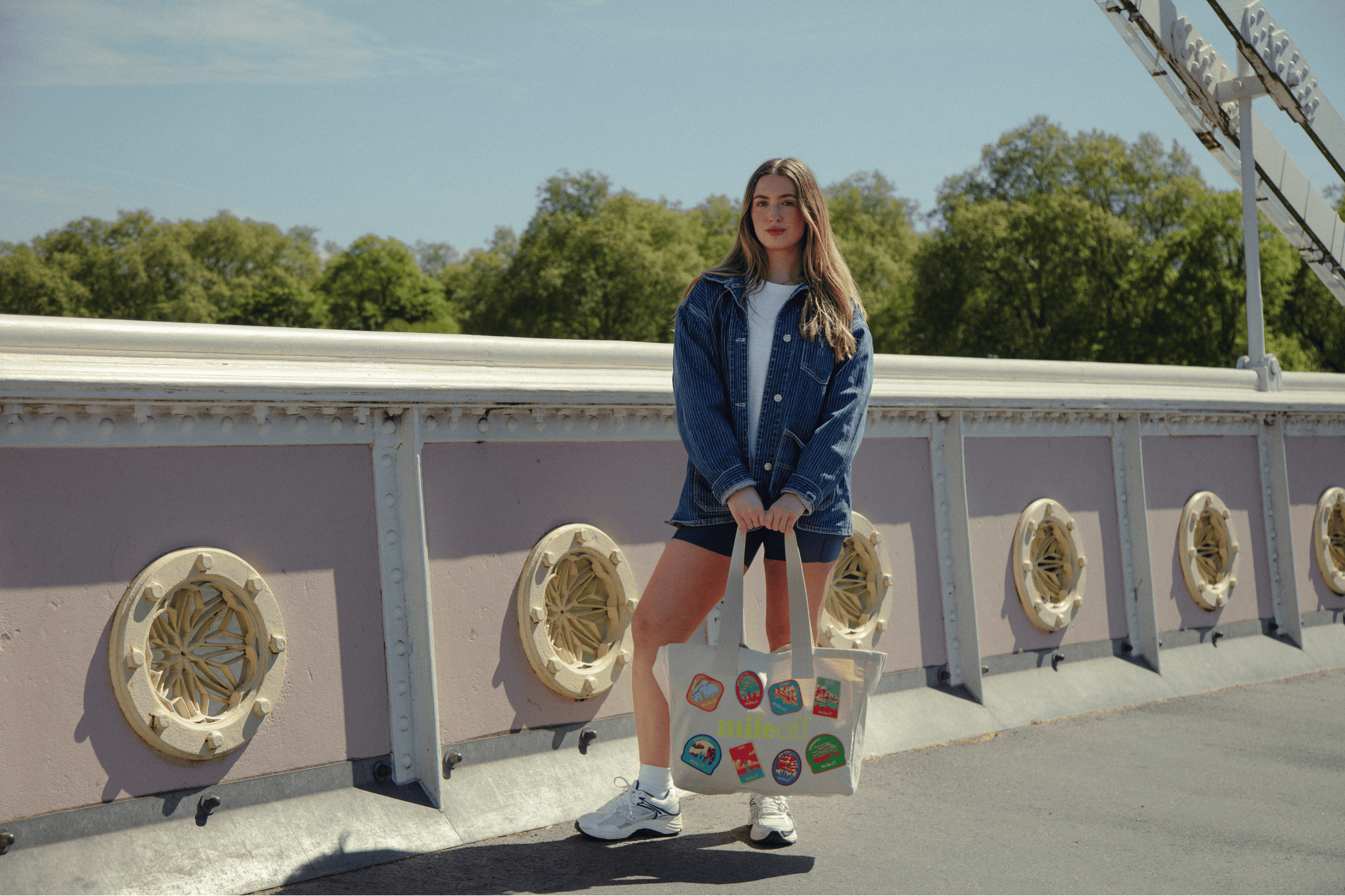 Woman holding a tote bag with stickers on a bridge