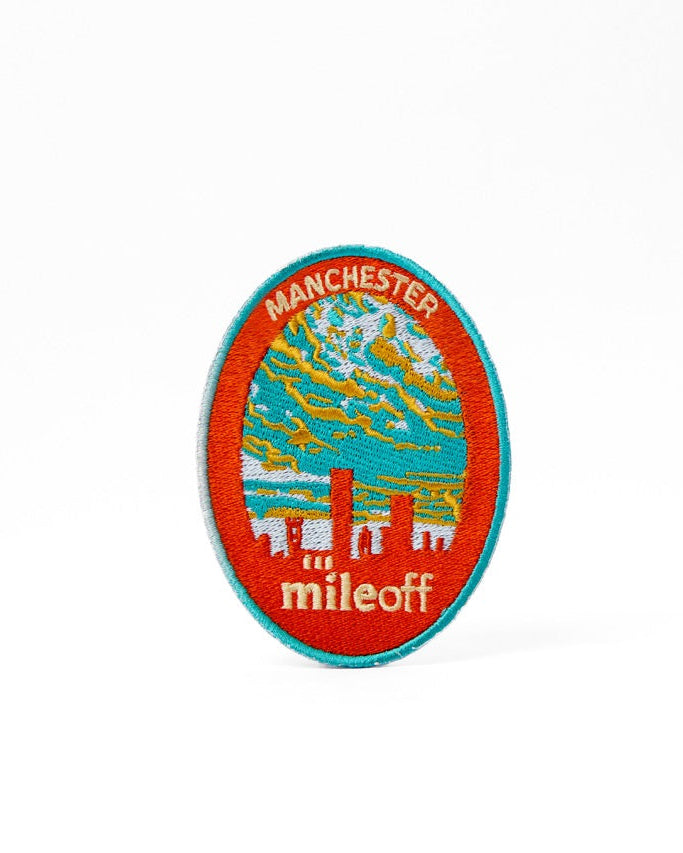 Circular badge with 'Manchester and mileoff' text and cityscape illustration on a white background