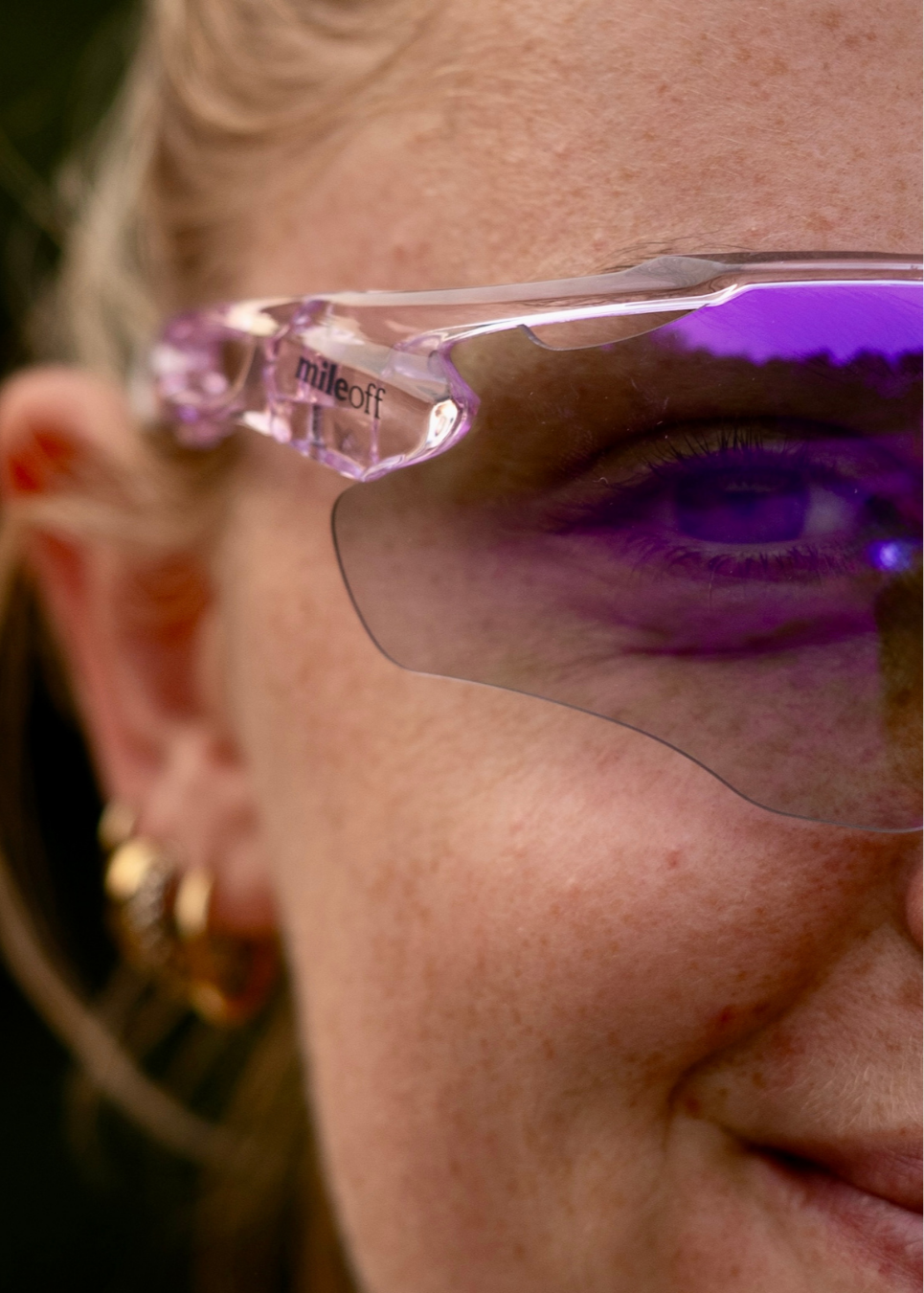 Close-up of a person wearing pink sunglasses with 'mileoff' branding.