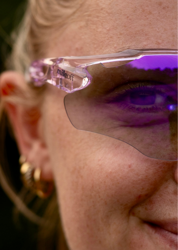 Close-up of a person wearing pink sunglasses with 'mileoff' branding.