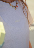 Person wearing a light grey sweatshirt with 'mileoff' logo, holding a green and yellow object.